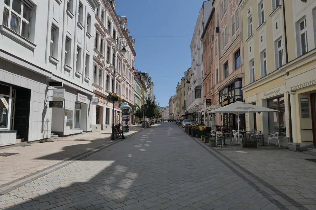 Das Bild zeigt eine Einkaufsstraße in Karlsbad. Links und rechts säumen schöne Altbauten in verschiedenen Farben die Fußgängerzone.